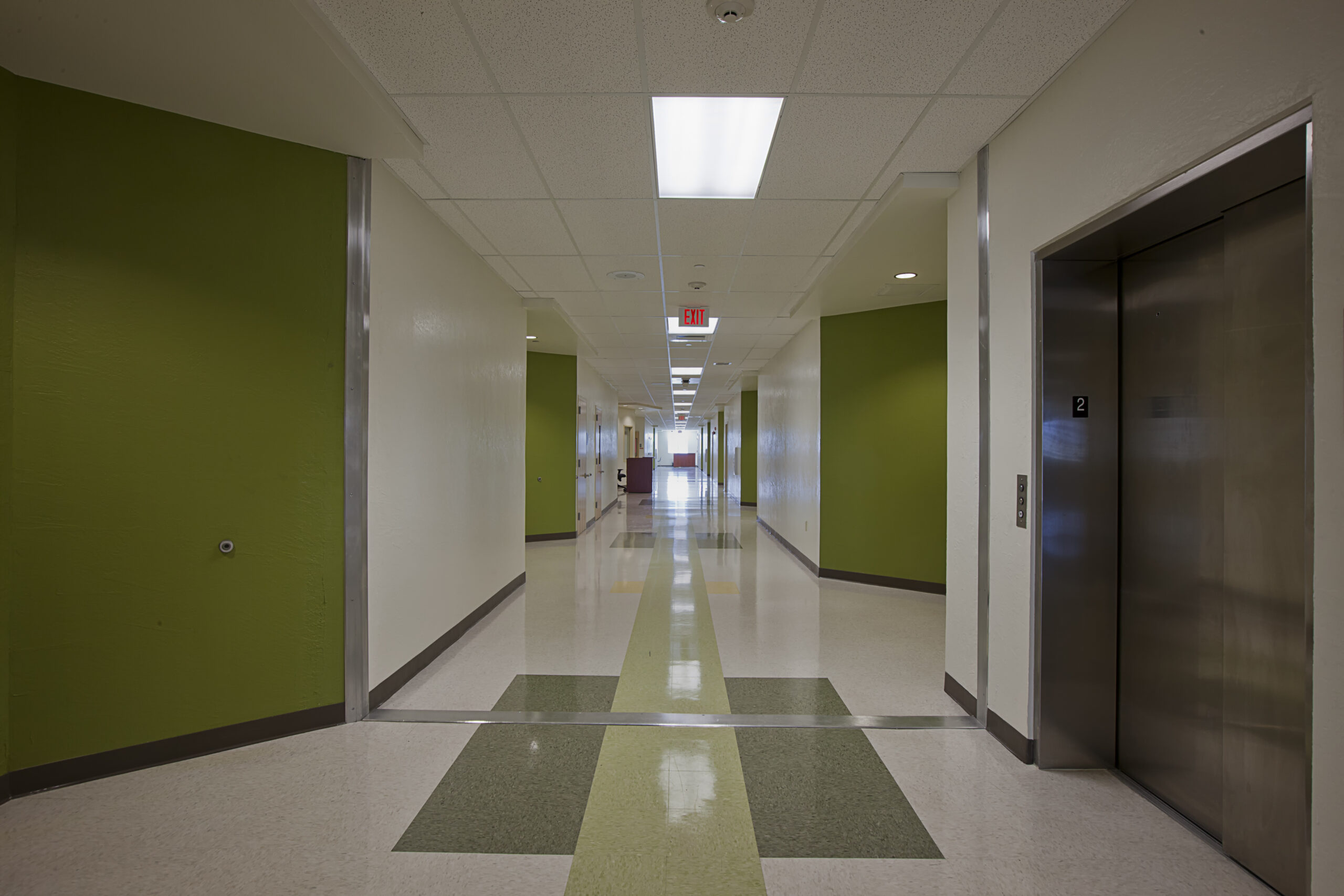 View of a green interior hallway and elevator of the Lanier-James Education Center